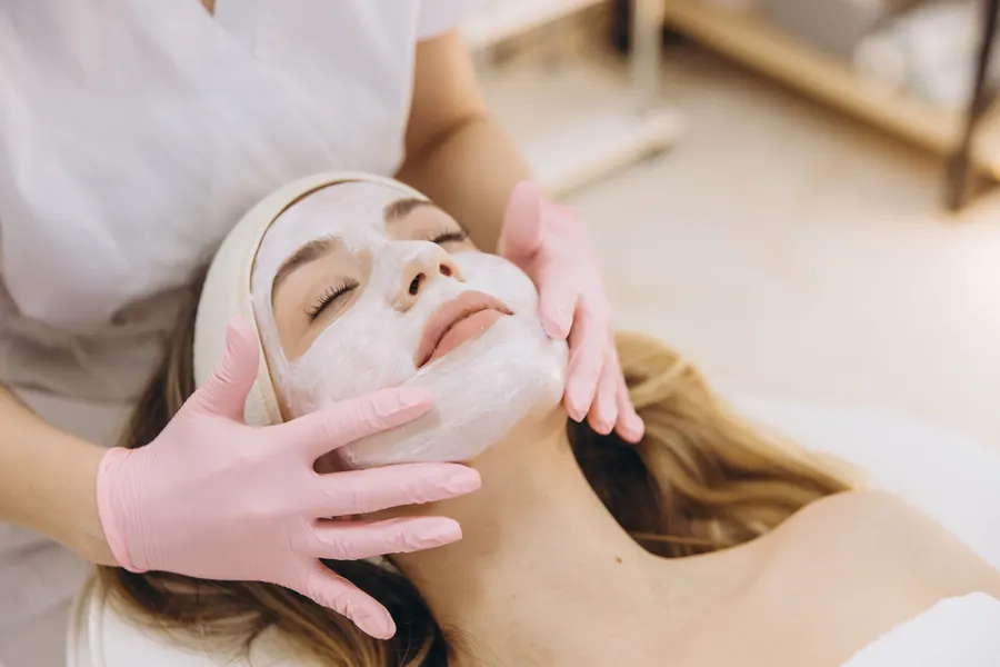 Esthetician applying a facial mask during a skin treatment